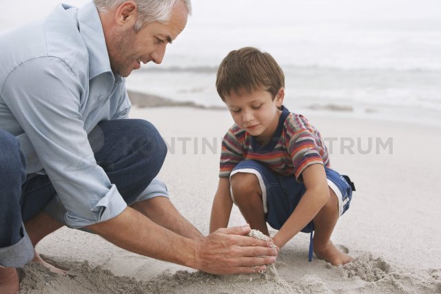 Keine Sorgen über Inkontinenz - Kind und Vater bauen eine Sandburg am Strand